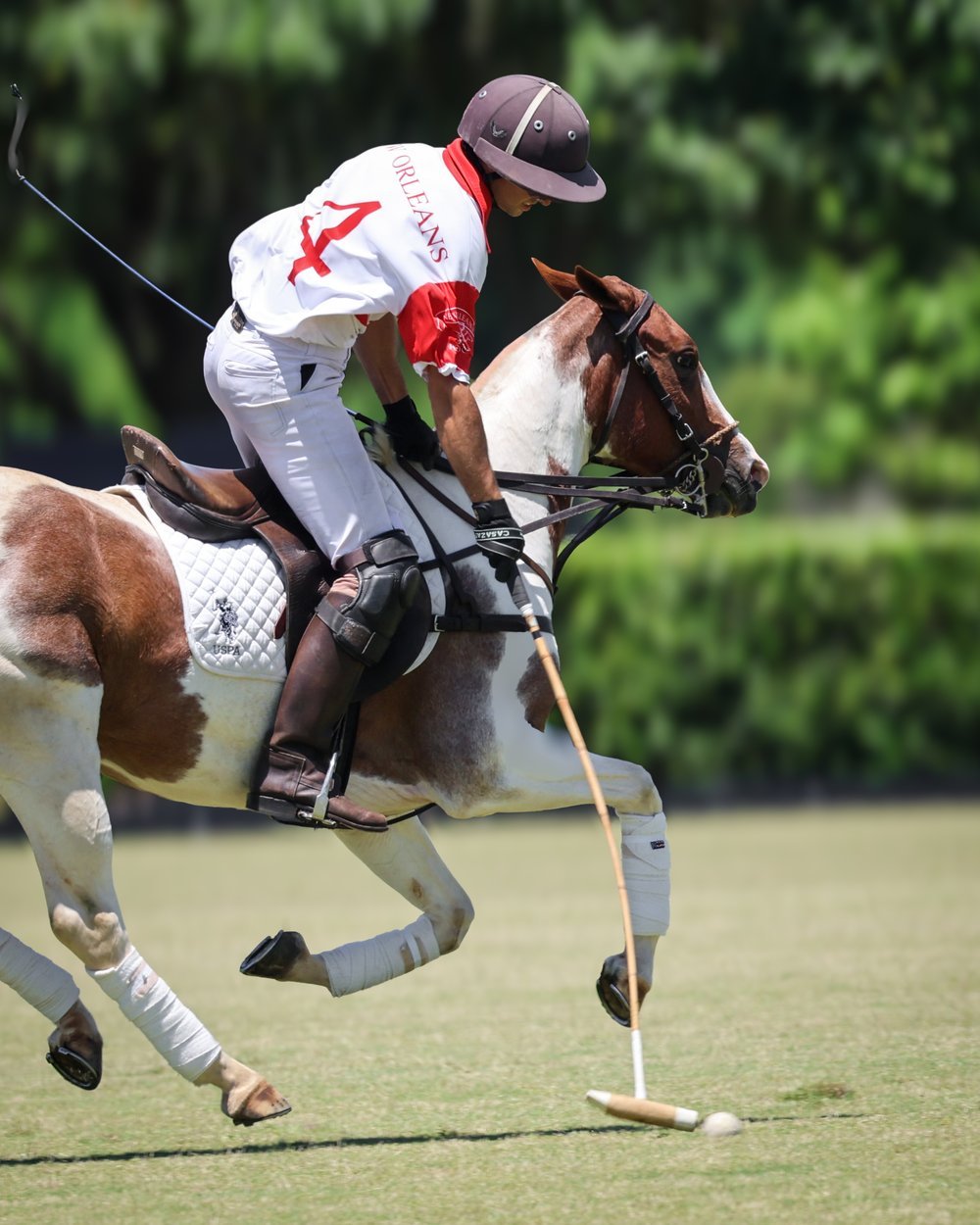 New Orleans Polo Club player in team jersey, mid-swing at Summergrove Farm, Folsom, Louisiana